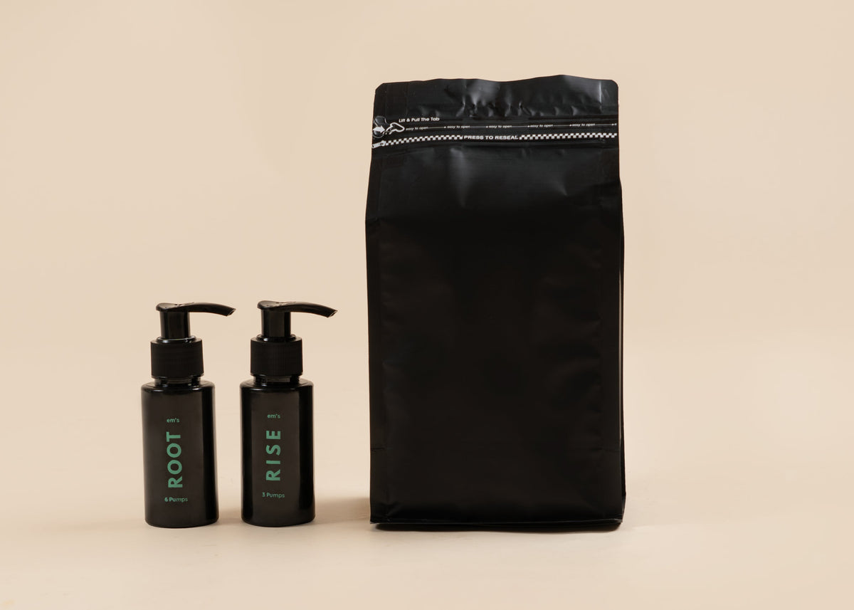 A black resealable pouch stands next to two small black pump bottles labeled ROOT and RISE on a warm beige background.