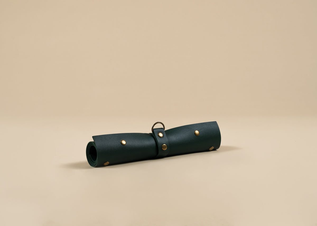 30x60cm in size, A dark forest green rolled leather pouch with brass studs and a metal ring, displayed on a warm beige background.