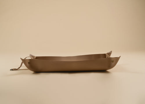 30x60cm in size, A minimalist, handcrafted leather tray in a warm taupe-brown color, featuring a small leather strap detail on one end, set against a solid beige background.