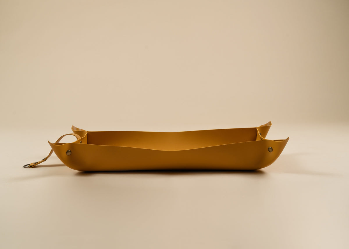 30x60cm in size, A yellow leather tray with a loop handle on one end, photographed on a clean, solid beige background.