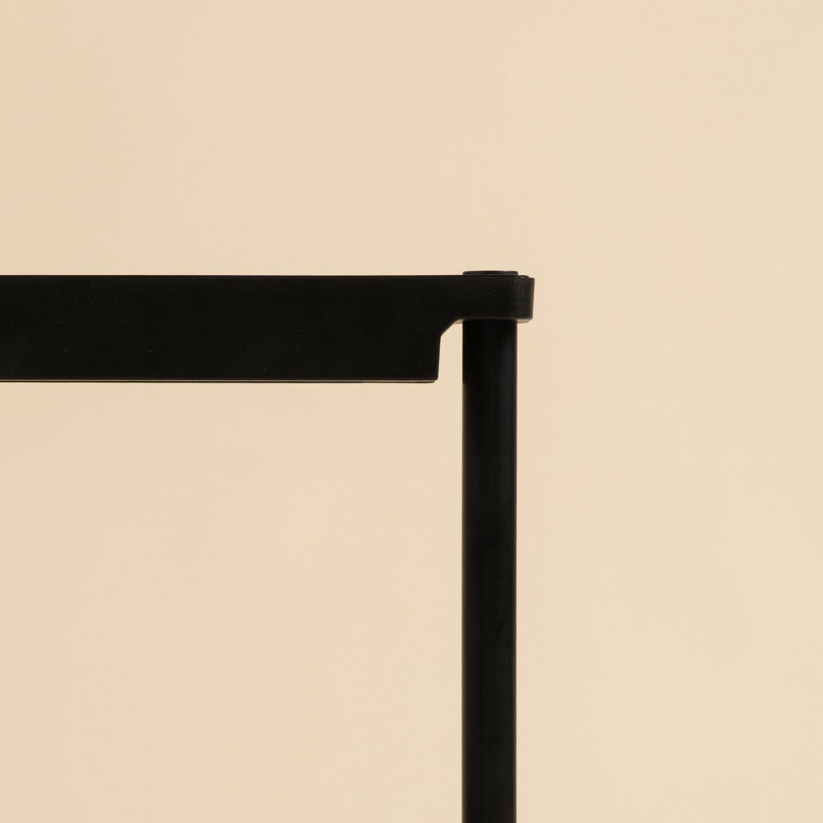 A black metal plant starter tray with four individual pots, branded 'em-Li' on the top bar, set against a solid beige background.