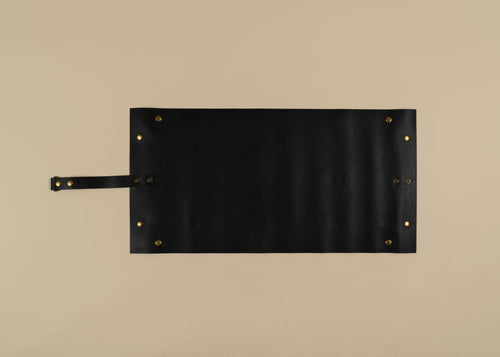 30x60cm in size, A black rectangular leather-like accessory with a strap on the left side and small brass-tone rivets at the corners, photographed flat against a warm beige background.