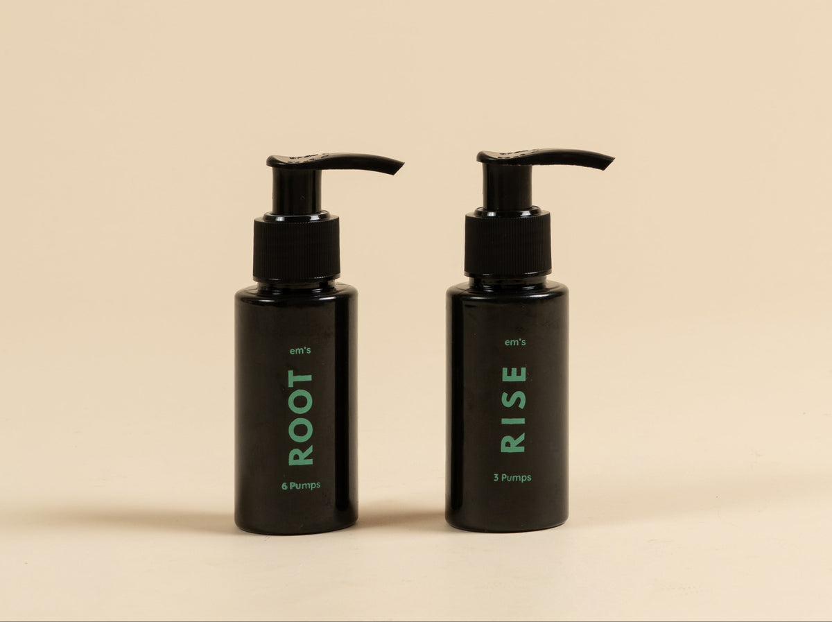 Two black pump bottles with green text, labeled ROOT and RISE, standing side by side on a warm beige background.