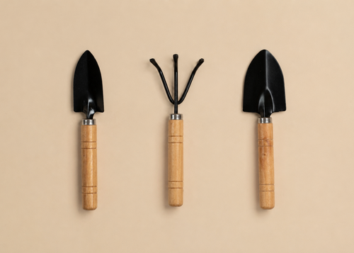 Three gardening hand tools with black metal heads and light wood handles, arranged vertically on a plain beige background.